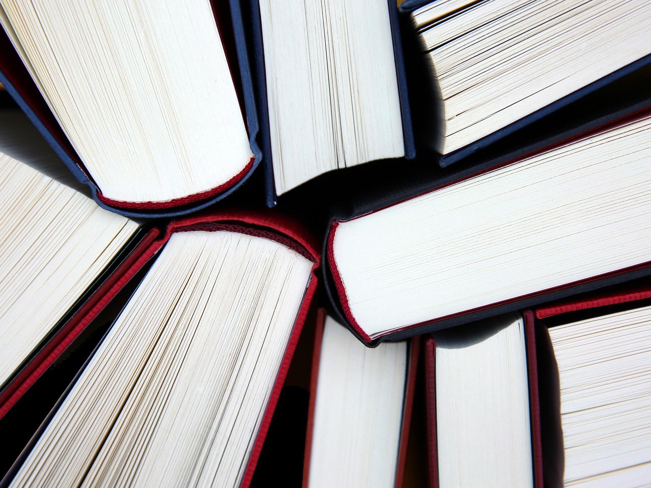 圖書館內研究論文與評審文件堆積於桌上，旁邊有筆記本電腦顯示文字